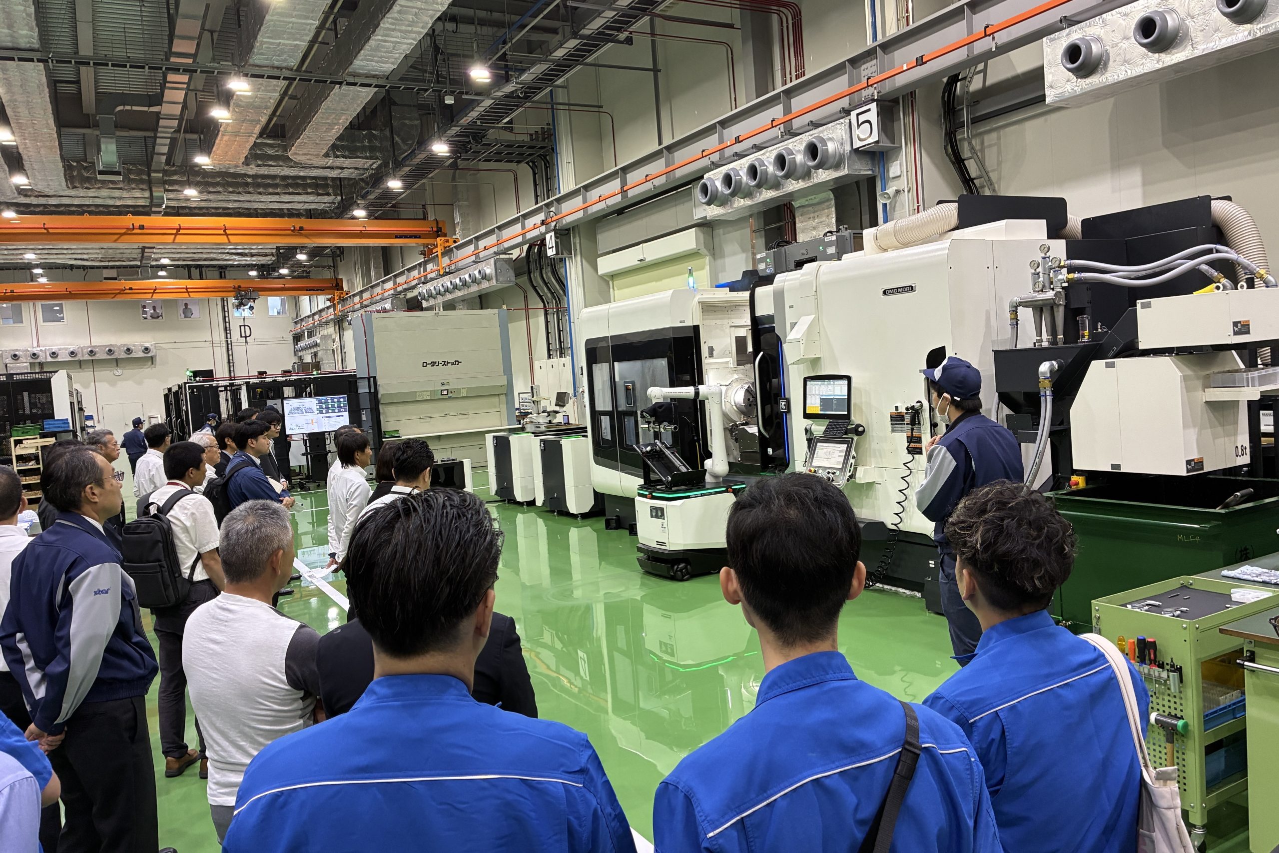 機械の前で説明を聞く参加者たち